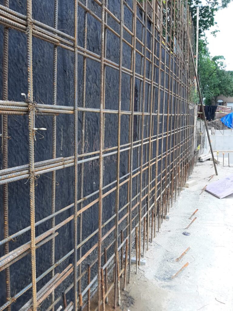 Rebar grid and drainage membrane on a long foundation wall